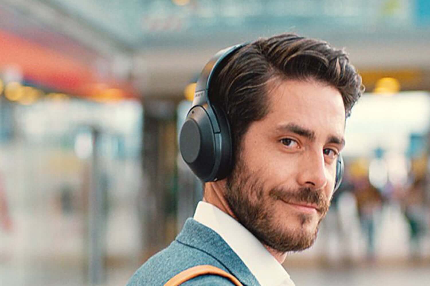 Seorang pria sedang belajar dengan mengenakan headphone over-ear warna hitam